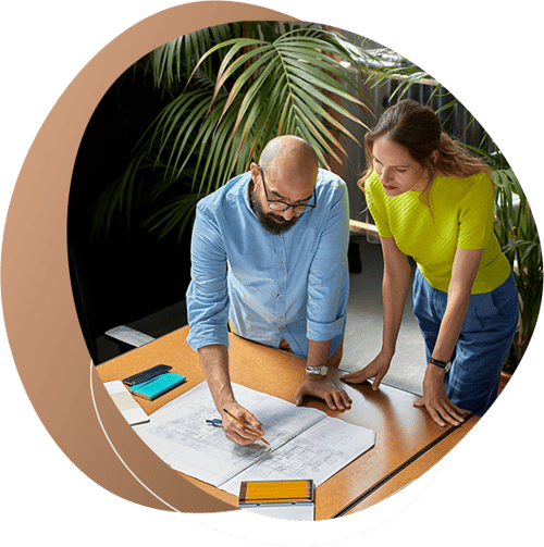Two people collaborate in marking up a design on a table